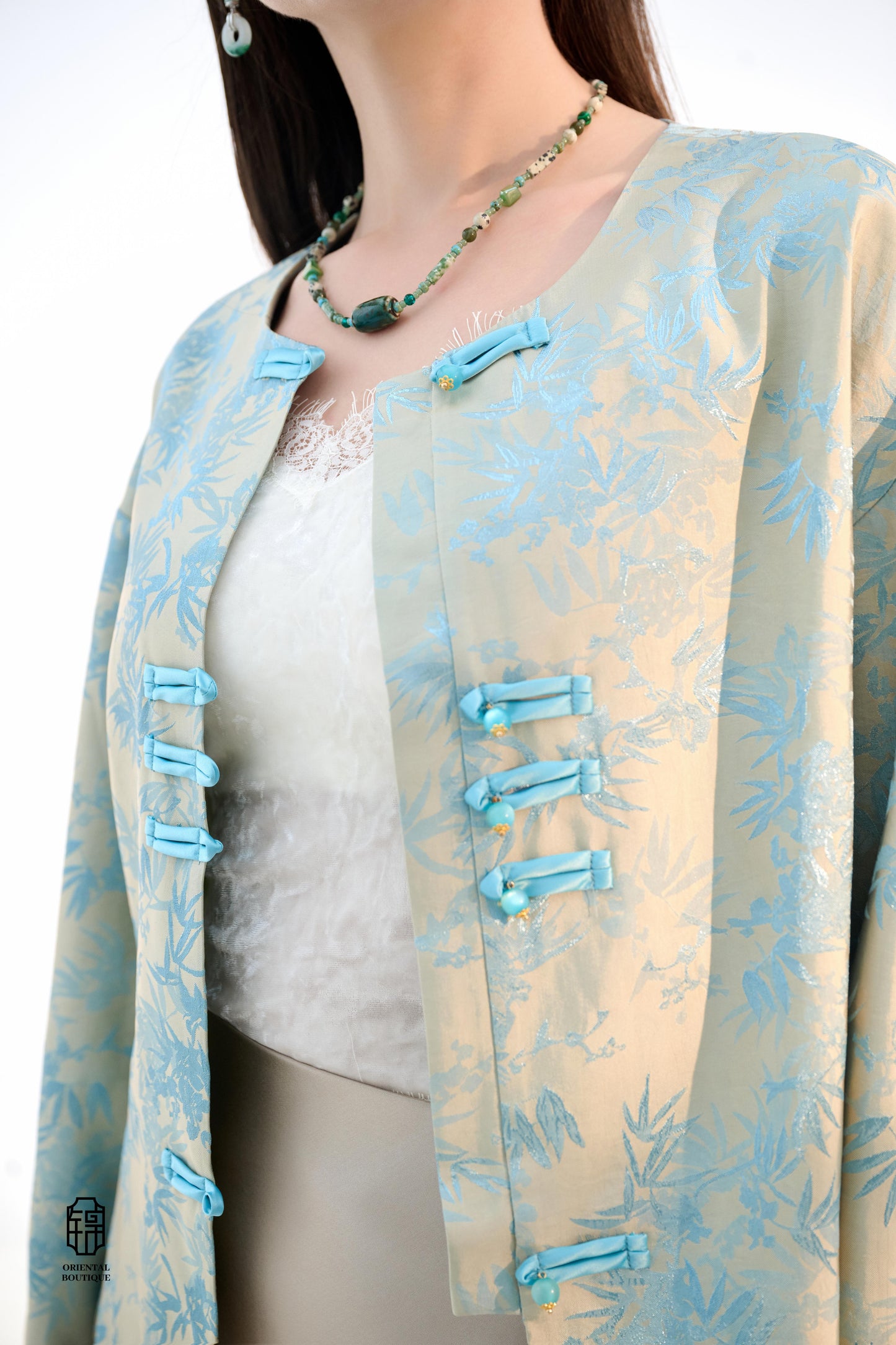 Bamboo Shadow Satin Long-Sleeve Top with Blue Knots,This Bamboo Shadow Satin Long-Sleeve Top features a graceful combination of light blue and beige with a subtle bamboo print. The design is accentuated by traditional Chinese blue knotted buttons and matc
