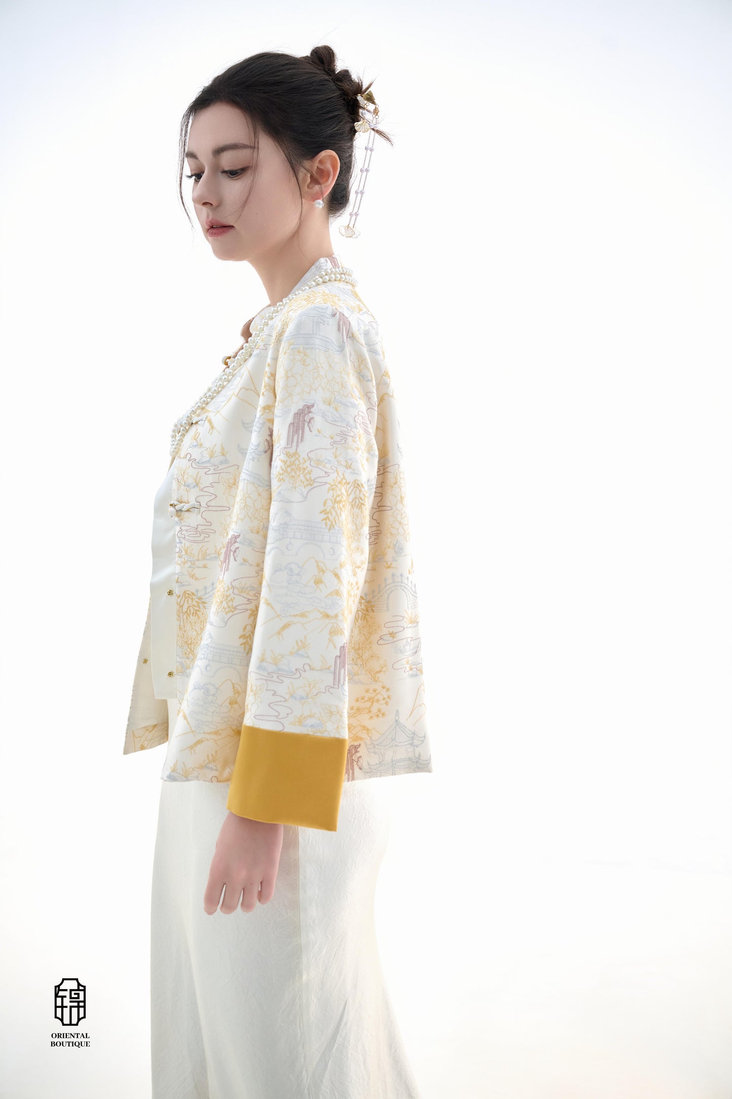 Scenic Brocade Jacket,The Scenic Brocade Jacket features intricate embroidered designs depicting traditional landscapes of mountains, pagodas, and natural scenery, showcasing an Oriental charm. With a base of soft ivory and accents of bright golden yellow